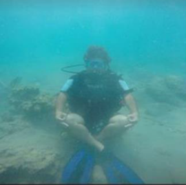 Original hazy underwater frame showing a seated scuba diver.